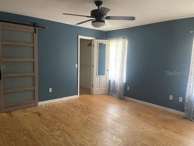 6051 NE 25th Ave, Ocala, FL 34479 - unfurnished room with a ceiling fan, a barn door, wood finished floors, and baseboards