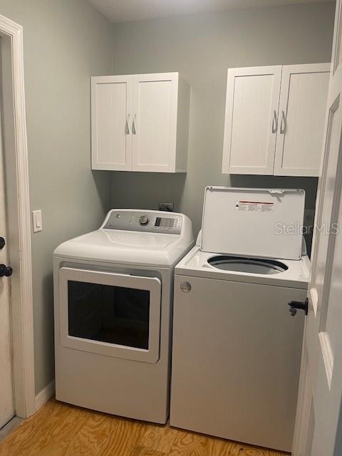 6051 NE 25th Ave, Ocala, FL 34479 - laundry room featuring cabinet space, washing machine and dryer, and light wood-style floors