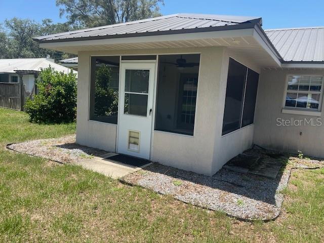 6051 NE 25th Ave, Ocala, FL 34479 - view of side of home featuring stucco siding, metal roof, and a sunroom