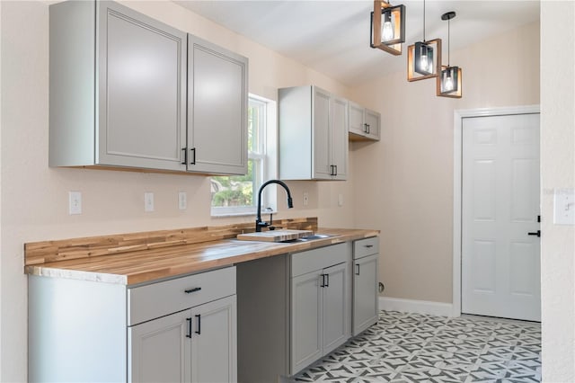 5193 NW 61st Ave, Ocala, FL 34482 - kitchen with a sink, butcher block countertops, light floors, hanging light fixtures, and baseboards