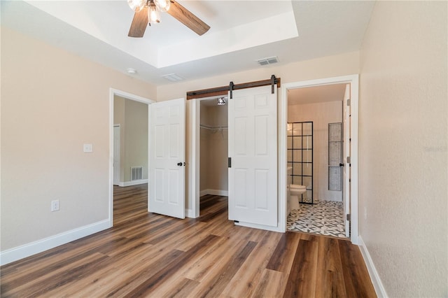 5193 NW 61st Ave, Ocala, FL 34482 - unfurnished bedroom featuring a barn door, a raised ceiling, wood finished floors, and baseboards
