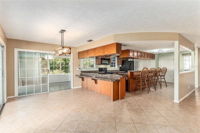 1404 SE 40th Ct, Ocala, FL 34471 - kitchen featuring a breakfast bar, black appliances, brown cabinets, a peninsula, and baseboards