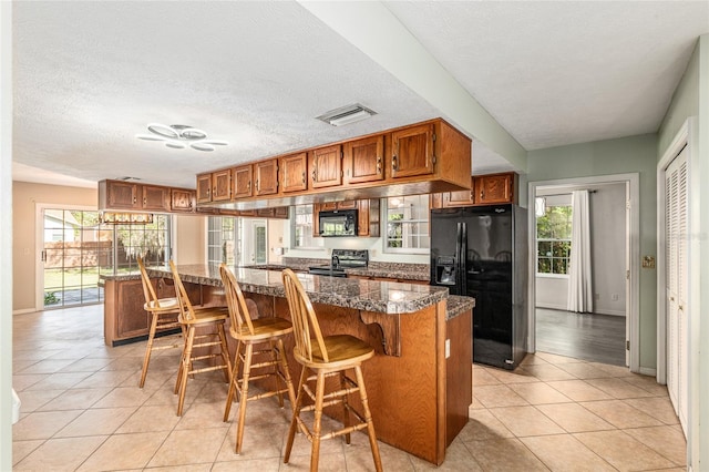 1404 SE 40th Ct, Ocala, FL 34471 - kitchen with black appliances, brown cabinetry, plenty of natural light, a kitchen breakfast bar, and a textured ceiling