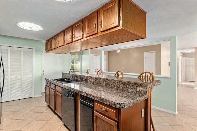 1404 SE 40th Ct, Ocala, FL 34471 - kitchen with black dishwasher, a sink, light tile patterned floors, a textured ceiling, and brown cabinets