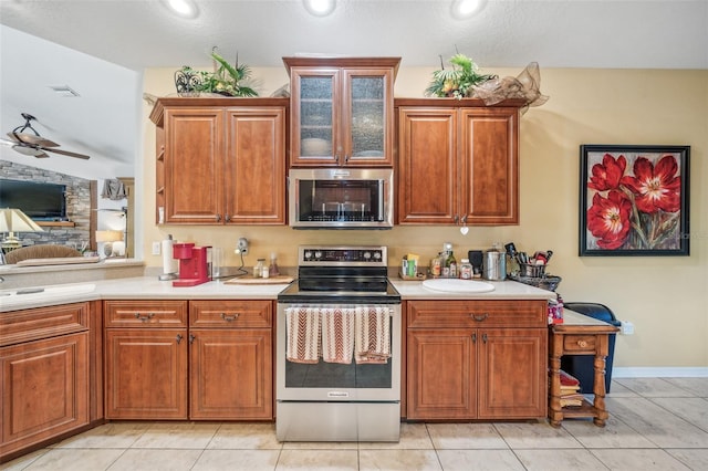 2948 W Henley Ln, Dunnellon, FL 34433 - kitchen with stainless steel appliances, light countertops, a ceiling fan, glass insert cabinets, and brown cabinets