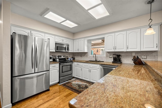 20861 SW 81st Loop, Dunnellon, FL 34431 - kitchen with appliances with stainless steel finishes, a sink, white cabinets, light wood finished floors, and pendant lighting