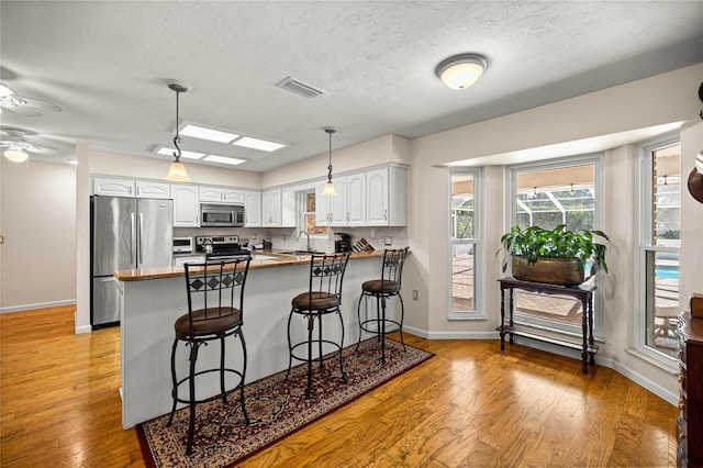 20861 SW 81st Loop, Dunnellon, FL 34431 - kitchen featuring stainless steel appliances, a peninsula, a sink, white cabinetry, and a textured ceiling