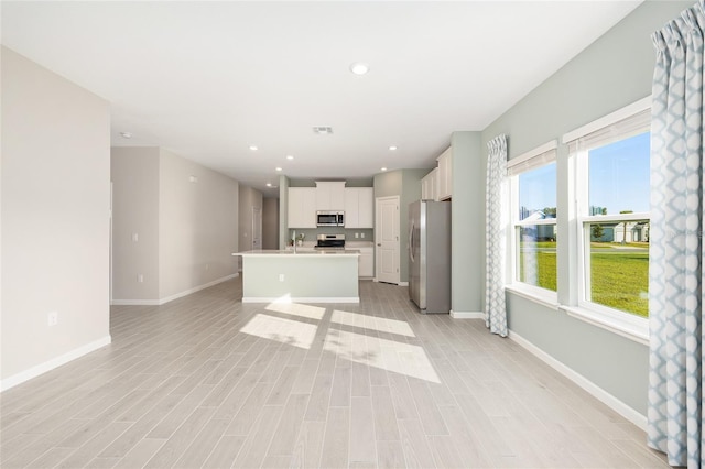 1875 NW 44 Court Rd, Ocala, FL 34482 - kitchen with stainless steel appliances, an island with sink, baseboards, light countertops, and white cabinetry