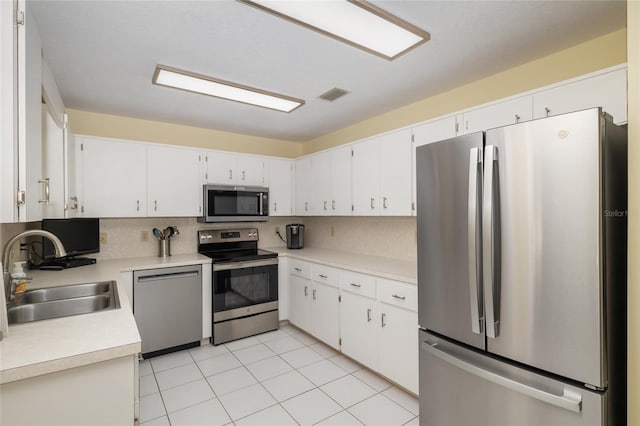 kitchen featuring stainless steel appliances, a sink, decorative backsplash, and light countertops
