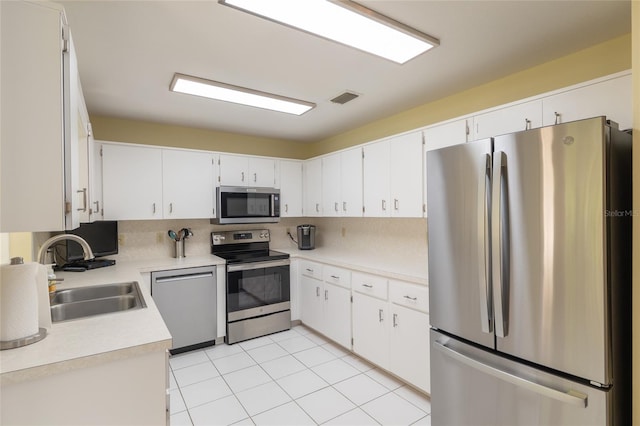 kitchen featuring appliances with stainless steel finishes, a sink, tasteful backsplash, light countertops, and light tile patterned floors