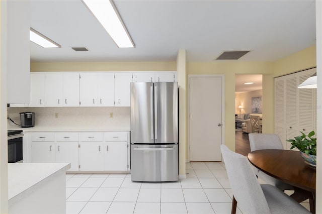kitchen with freestanding refrigerator, light countertops, white cabinets, and light tile patterned floors