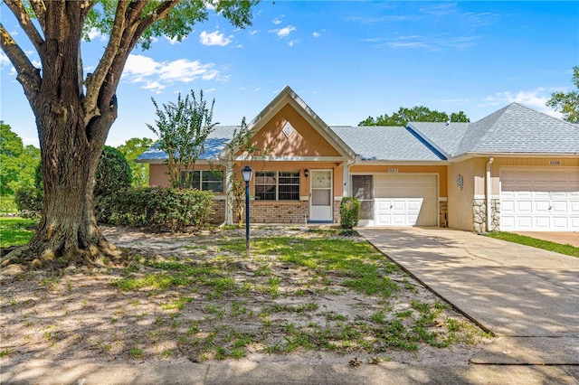 view of front of property featuring a garage, concrete driveway, stucco siding, and roof with shingles