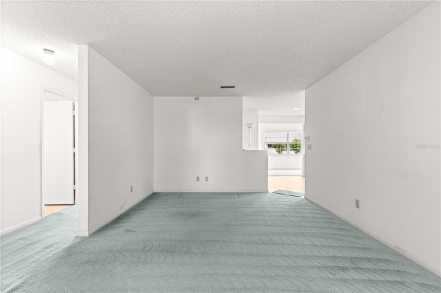 carpeted empty room with a textured ceiling and baseboards