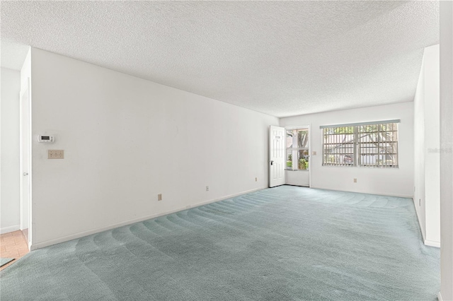 spare room featuring carpet, a textured ceiling, and baseboards