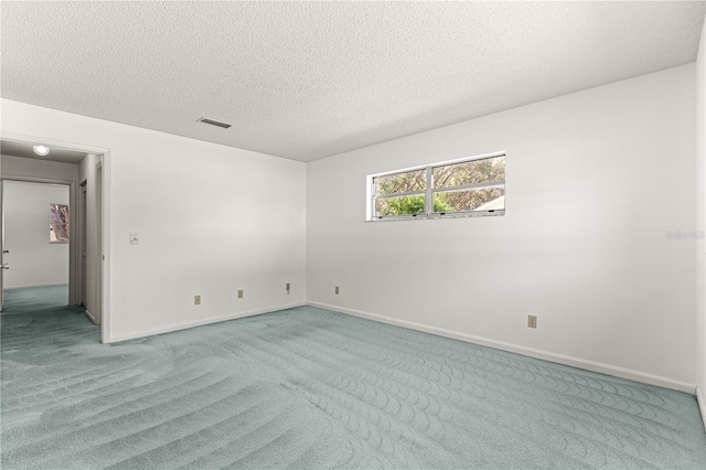 carpeted spare room with a textured ceiling and baseboards