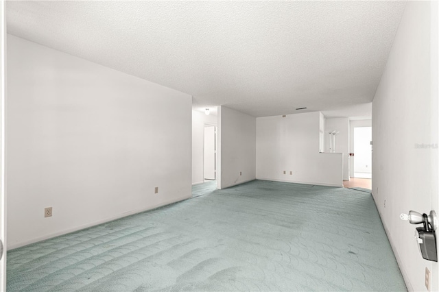 carpeted spare room featuring a textured ceiling and baseboards