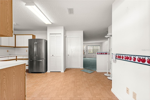 kitchen with freestanding refrigerator, light countertops, baseboards, white cabinetry, and a textured ceiling