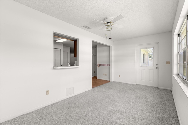 unfurnished room featuring ceiling fan, carpet, a textured ceiling, and baseboards