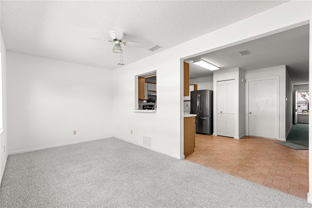 unfurnished living room featuring a ceiling fan, light carpet, a textured ceiling, and baseboards