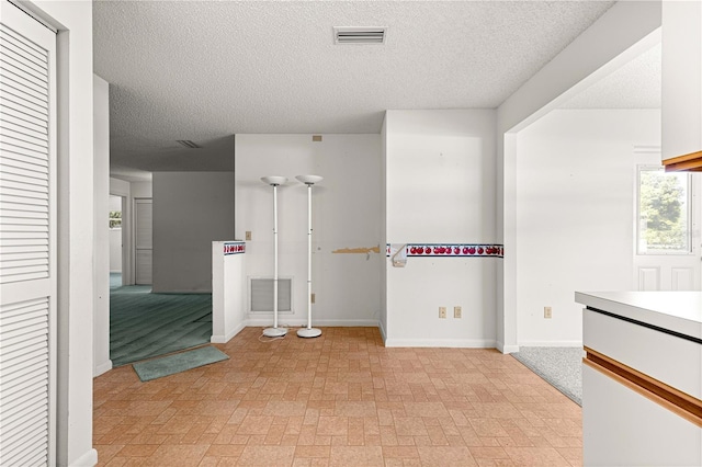 spare room with a textured ceiling and baseboards