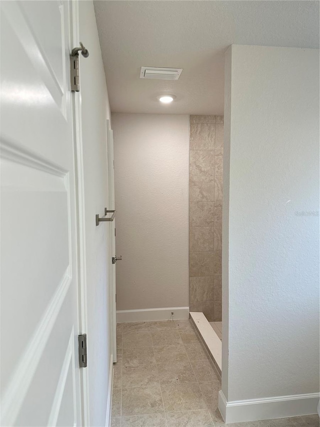bathroom with tiled shower and baseboards