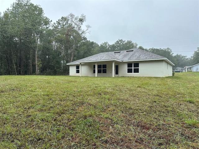 rear view of house with a yard and stucco siding