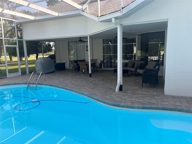 outdoor pool with ceiling fan, a patio, glass enclosure, and an outdoor hangout area