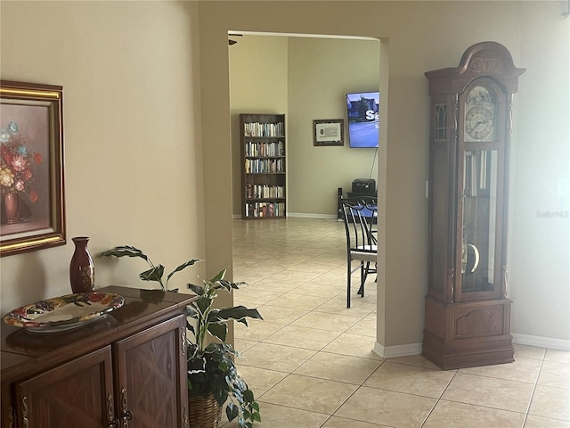 hall featuring light tile patterned flooring and baseboards