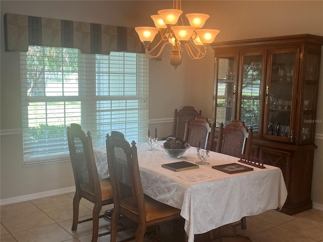 dining space with a chandelier, light tile patterned floors, and baseboards