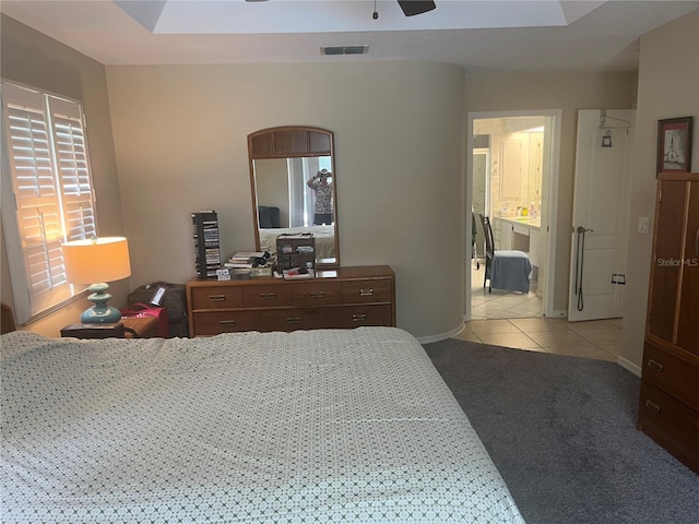 bedroom featuring light carpet, light tile patterned flooring, baseboards, and ensuite bath