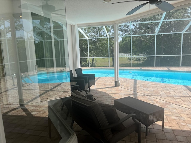 swimming pool with ceiling fan, a patio, and a lanai