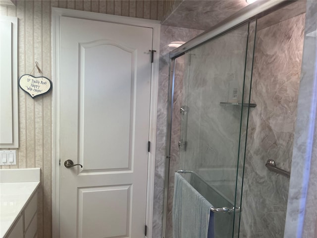full bath featuring a marble finish shower and vanity