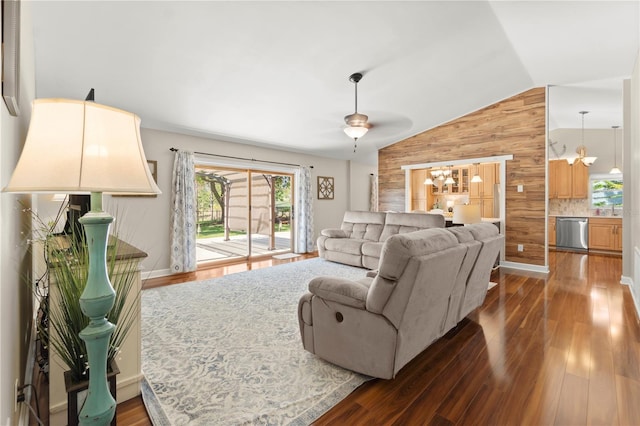 living room with wood walls, healthy amount of natural light, vaulted ceiling, dark wood-type flooring, and a chandelier