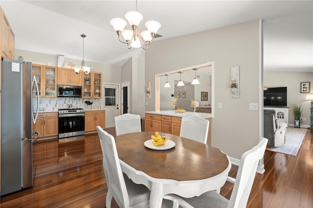 dining area featuring a chandelier, dark wood-style floors, vaulted ceiling, and baseboards