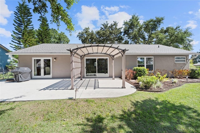rear view of house featuring french doors, a yard, stucco siding, a patio area, and a pergola