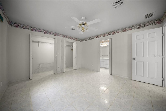 4992 NW 31st St, Ocala, FL 34482 - unfurnished bedroom featuring baseboards, light tile patterned floors, two closets, a ceiling fan, and connected bathroom
