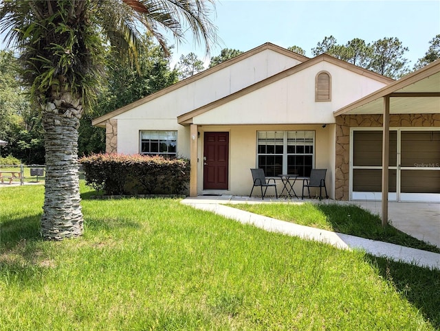 21298 SW Peach Blossom St, Dunnellon, FL 34431 - view of front of property featuring a front yard, a garage, driveway, stone siding, and stucco siding