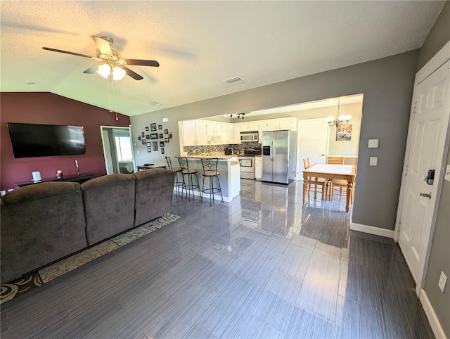 21298 SW Peach Blossom St, Dunnellon, FL 34431 - living room featuring lofted ceiling, ceiling fan, a chandelier, baseboards, and a textured ceiling
