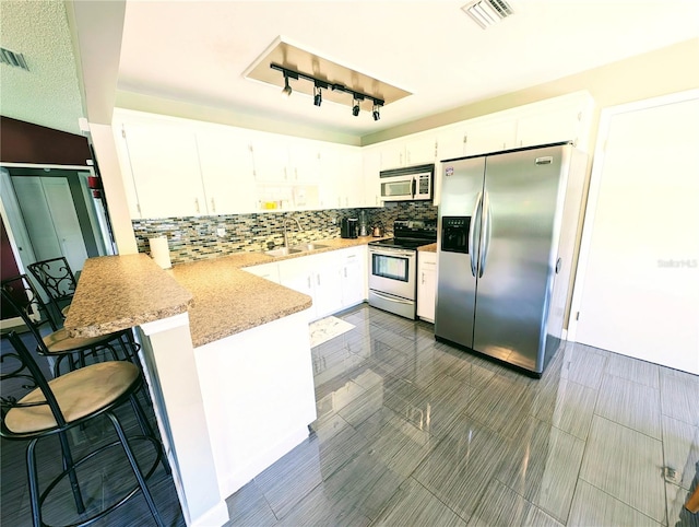 21298 SW Peach Blossom St, Dunnellon, FL 34431 - kitchen featuring appliances with stainless steel finishes, a peninsula, tasteful backsplash, white cabinetry, and a sink