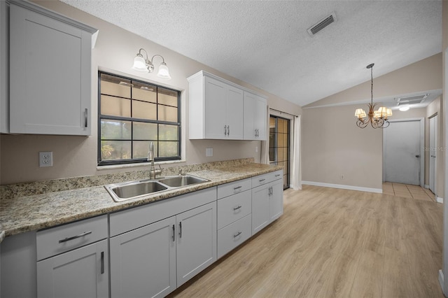 23 Larch Crse, Ocala, FL 34480 - kitchen featuring a sink, lofted ceiling, a chandelier, a textured ceiling, and light wood-style flooring