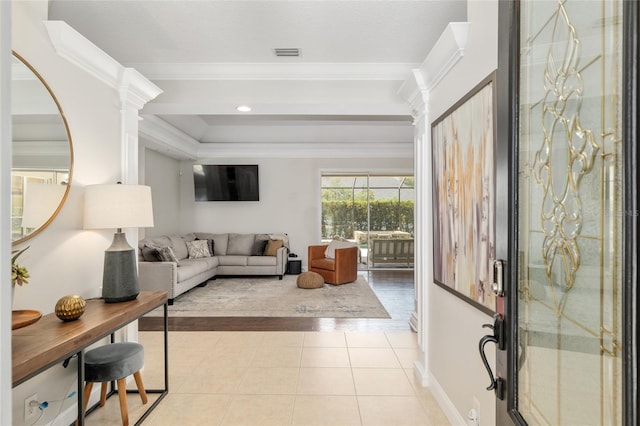 living room with decorative columns, ornamental molding, light tile patterned flooring, a raised ceiling, and baseboards