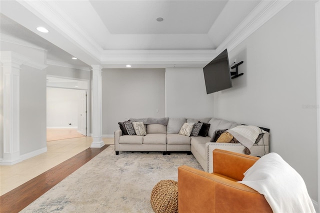 living area featuring ornate columns, wood finished floors, ornamental molding, recessed lighting, and a tray ceiling