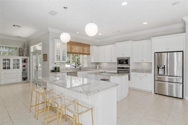 kitchen with stainless steel appliances, a center island, healthy amount of natural light, light tile patterned floors, and ornamental molding