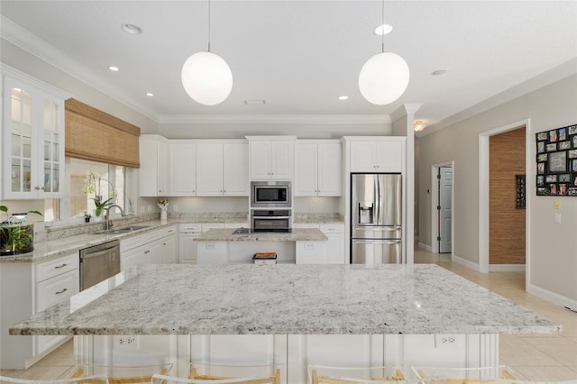 kitchen with appliances with stainless steel finishes, a kitchen island, crown molding, white cabinets, and a sink