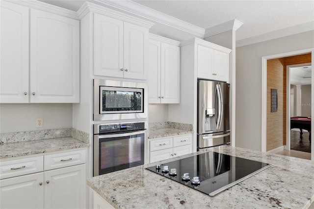 kitchen with appliances with stainless steel finishes, white cabinets, light stone counters, crown molding, and a textured ceiling