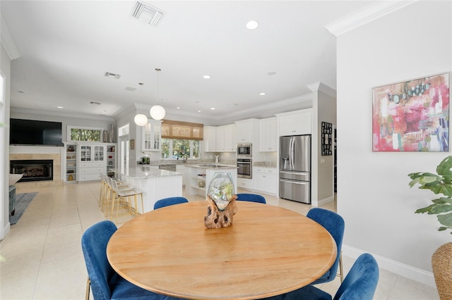dining space with crown molding, light tile patterned floors, a glass covered fireplace, recessed lighting, and baseboards