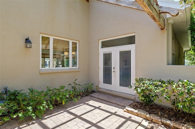 property entrance with french doors, stucco siding, and a patio area