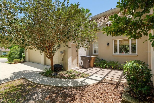 view of side of property featuring concrete driveway, a garage, and stucco siding