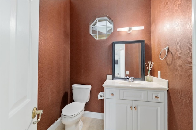 bathroom with toilet, vanity, baseboards, and tile patterned floors