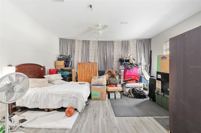 bedroom with light wood-style flooring, an accent wall, wallpapered walls, and ceiling fan